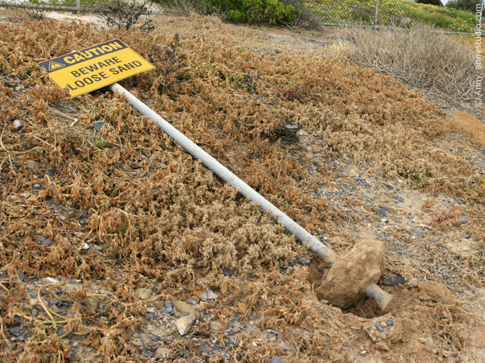 Beware loose sand sign, installed on loose sand and fallen.