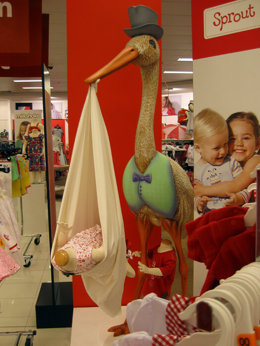 Stork and headless baby dummy display in a department store.